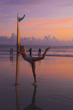 Woman surfer with surfboard at sunset, Bali.