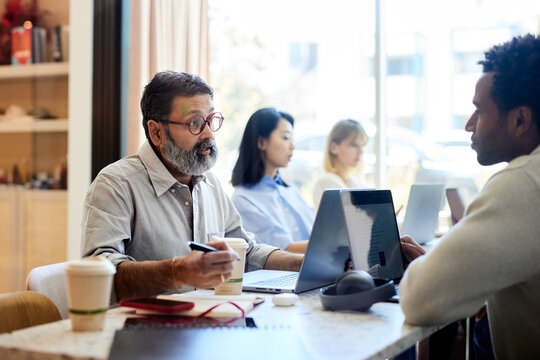 Mature businessman explaining coworker during meeting in cafe