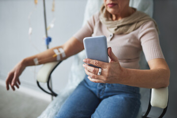 Closeup of senior woman using smartphone during chemotherapy treatment, copy space