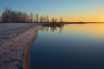 Morning hoarfrost on shore of lake and sunrise: nature of Northern Europe, Karelia, cold autumn morning.