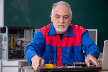 Old repairman repairing computers in the classroom