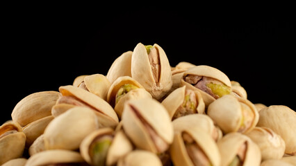 Heap of salted roasted pistachios on black background