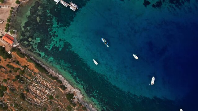 View from above, aerial view of a transparent and turquoise sea with some boats and yachts. Mediterranean sea coast, Knidos Ancient city, Datca, Turkey. Summertime vacation and travel to seaside