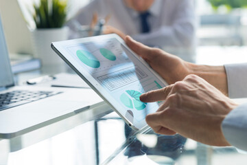 Business person analyzing financial statistics displayed on the tablet screen.