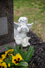 A small white angel statue on a cemetery gravestone