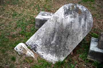 Toppled ancient gray gravestone partially buried in grass