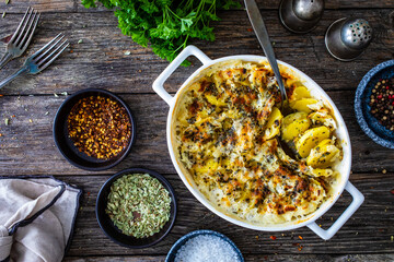 Potato casserole with mozzarella cheese and bechamel sauce on wooden table