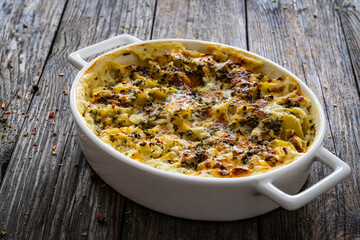 Potato casserole with mozzarella cheese and bechamel sauce on wooden table