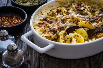 Potato casserole with mozzarella cheese and bechamel sauce on wooden table
