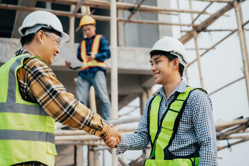 Construction workers, architects and engineers shake hands while working for teamwork and cooperation after completing an agreement in an office facility, successful cooperation concept.