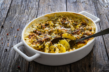 Potato casserole with mozzarella cheese and bechamel sauce on wooden table