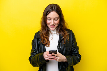 Young caucasian woman isolated on yellow background sending a message with the mobile