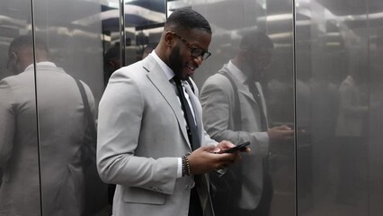 Stylish Afro-American Business Man Making A Call And Typing In Elevator 
