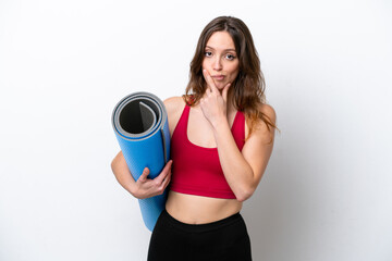 Young sport caucasian woman going to yoga classes while holding a mat isolated on white background thinking