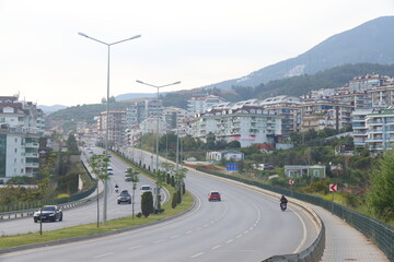 View of the highway, houses and mountains in Alanya, orange groves. Evening time, Türkiye, April 2023.