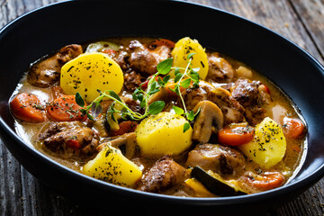 Delicious stew - cooked vegetables with roast meat on wooden table
