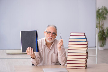 Old male teacher sitting in the classroom