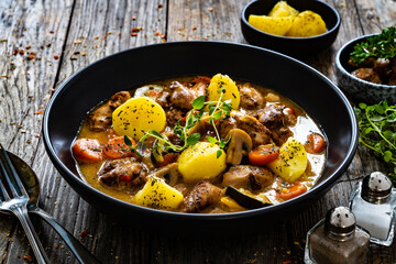 Delicious stew - cooked vegetables with roast meat on wooden table
