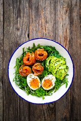 Salmon salad - smoked salmon, hard boiled eggs, avocado and leafy greens on wooden table
