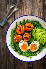 Salmon salad - smoked salmon, hard boiled eggs, avocado and leafy greens on wooden table
