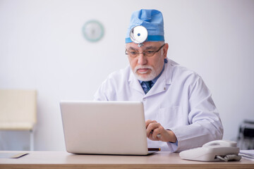 Old male docror otolaryngologist working in the clinic