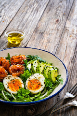 Salmon salad - smoked salmon, hard boiled eggs, avocado and leafy greens on wooden table
