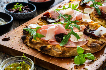 Pinsa Romana with mortadella, parmesan cheese and vegetables on wooden table
