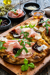 Pinsa Romana with mortadella, parmesan cheese and vegetables on wooden table
