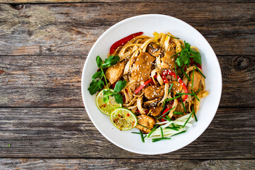 Asian food - chicken nuggets, noodles and stir fried vegetables on wooden table
