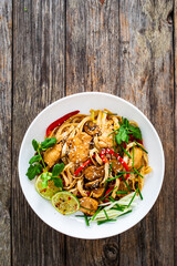 Asian food - chicken nuggets, noodles and stir fried vegetables on wooden table
