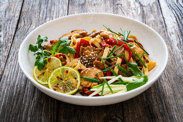 Asian food - chicken nuggets, noodles and stir fried vegetables on wooden table
