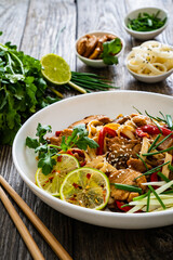 Asian food - chicken nuggets, noodles and stir fried vegetables on wooden table
