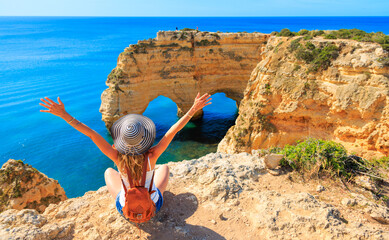 Woman tourist enjoying panoramic view of beautiful algarve heart shaped cliff on atlantic ocean-...