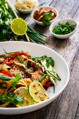 Asian food - chicken nuggets, noodles and stir fried vegetables on wooden table
