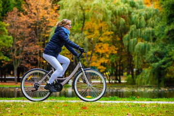 Fototapeta premium Woman riding bicycle in city park 
