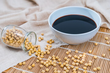 Lots of soybeans and a bowl of soy sauce spread on a bamboo mat