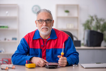 Old male repairman repairing computer