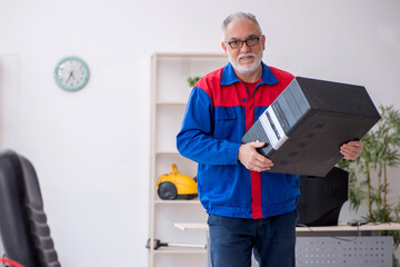 Old male repairman repairing computer