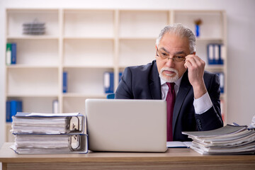 Old male employee sitting at workplace