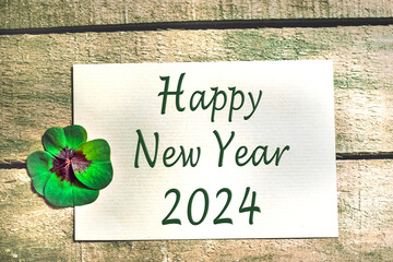 Glücksklee vor Holz mit Text in englisch Happy New Year 2024