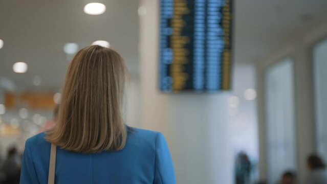 Woman in business suit in checking her flight in airport.