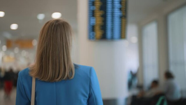Woman in business suit in checking her flight in airport.