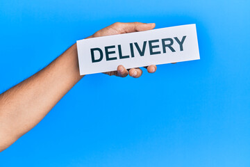 Hand of caucasian man holding paper with delivery word over isolated blue background