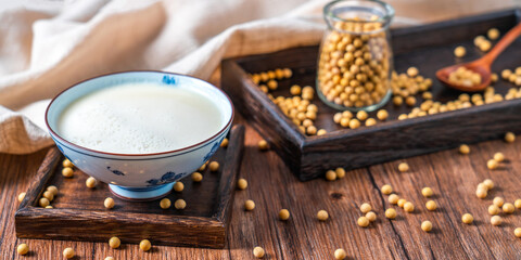 Many soybeans and a bowl of soy milk spilled on the table