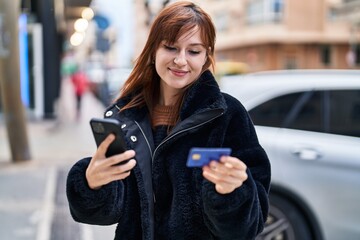 Young woman using smartphone and credit card at street