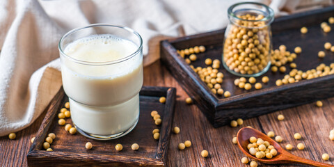 Many soybeans and a bowl of soy milk spilled on the table