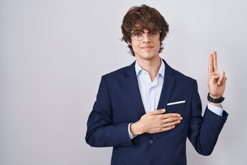 Hispanic business young man wearing glasses smiling swearing with hand on chest and fingers up,...