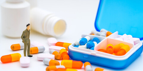 Pillbox, pills, capsules and toy figures isolated on white background