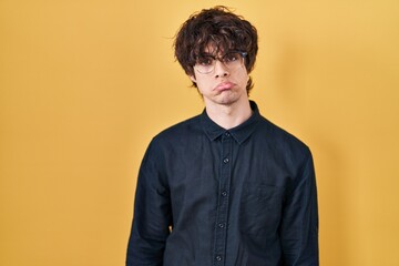 Young man wearing glasses over yellow background depressed and worry for distress, crying angry and afraid. sad expression.