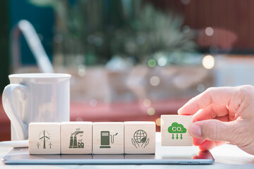 Carbon neutrality and net zero concepts. Hand-place wooden cubes bearing the netzero symbols for...